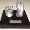 2- silver hand & foot cast on black granite plinth